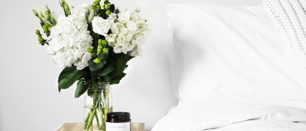 Κρεβάτι με κομοδίνο στο πλάι και λουλούδια
