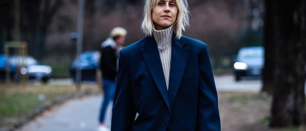 γυναίκα περπατά στην εβδομάδα μόδας με σακάκι και πουλόβερ