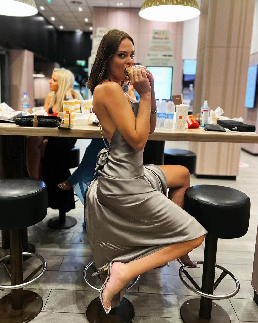 Η Υβόννη Μπόσνιακ τρώει ένα μπέργκερ φορώντας ένα glam σέξι φόρεμα 