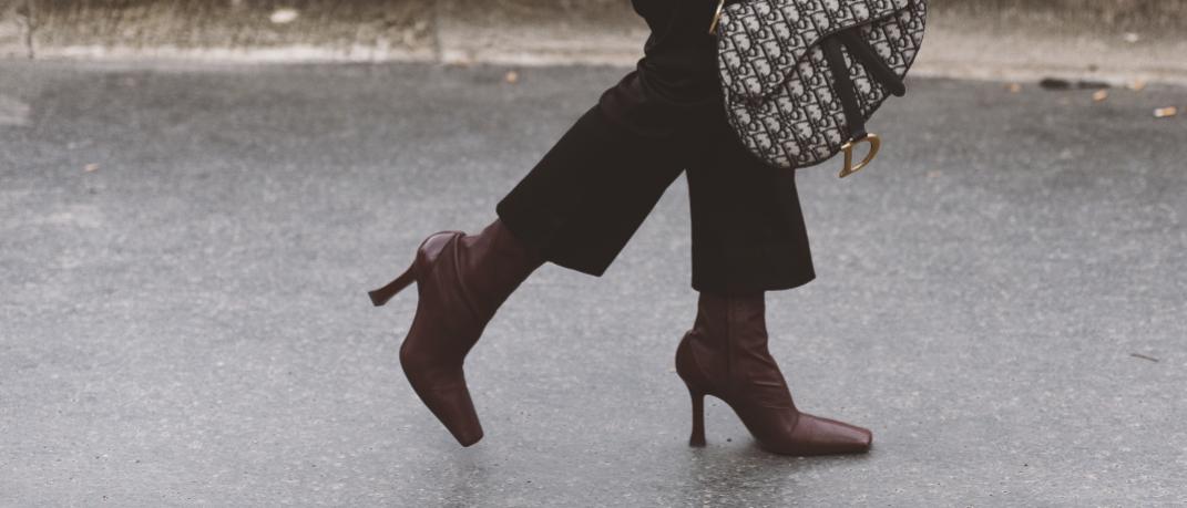 γυναίκα περπατά με τσάντα και μπότες στο δρόμο