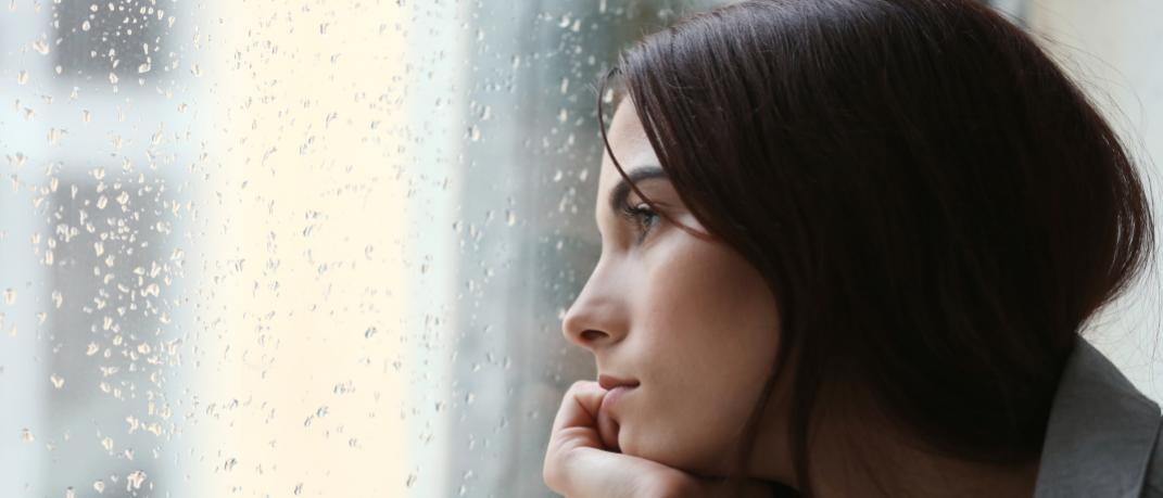 Μια μελαχρινή γυναίκα κοιτάζει το παράθυρο που βρέχει 