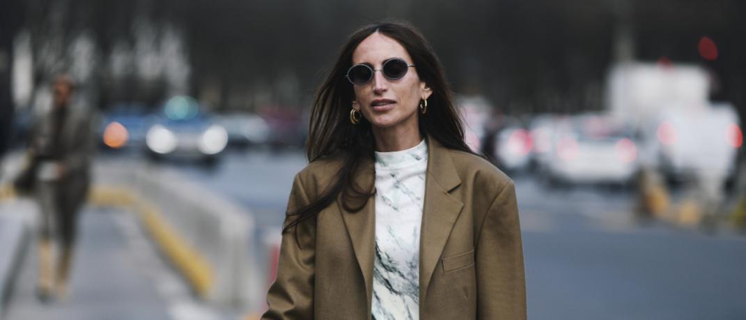 γυναίκα με σακάκι και γυαλιά περπατά στην εβδομάδα μόδας