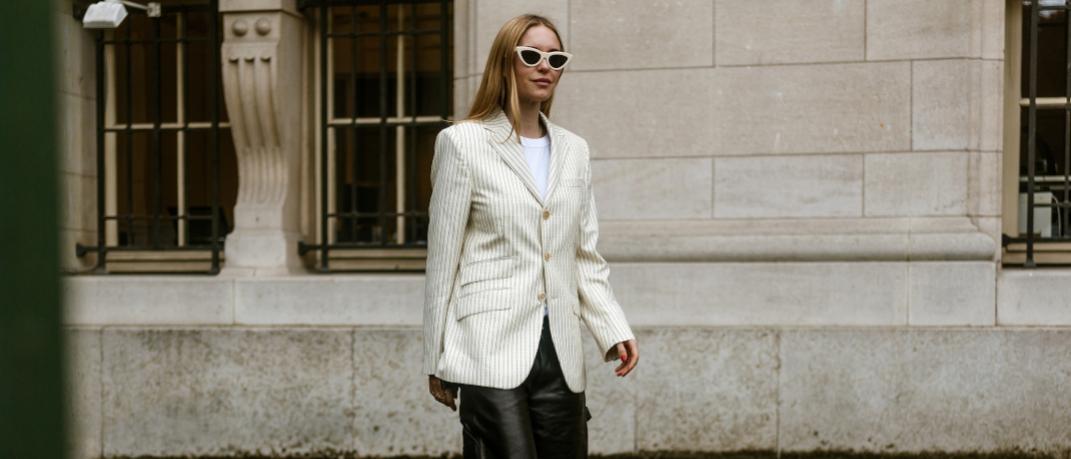 γυναίκα περπατά με σακάκι και γυαλιά στην εβδομάδα μόδας