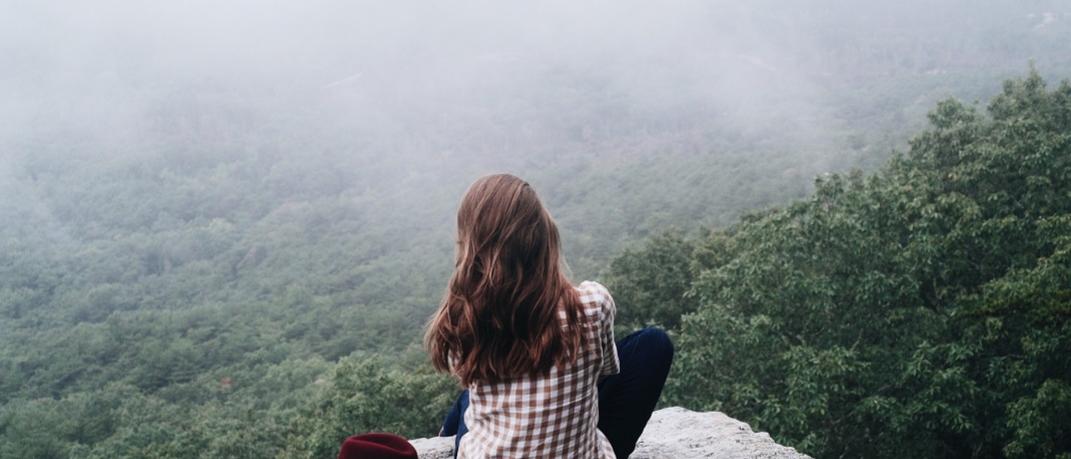 Γυναίκα κάθεται πλάτη και φορά καρό πουκάμισο με θέα δάσος