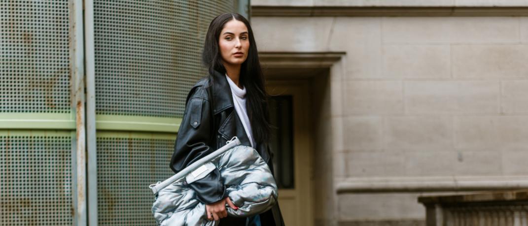 γυναίκα με δερμάτινο μπουφάν και τσάντα περπατά στην εβδομάδα μόδας
