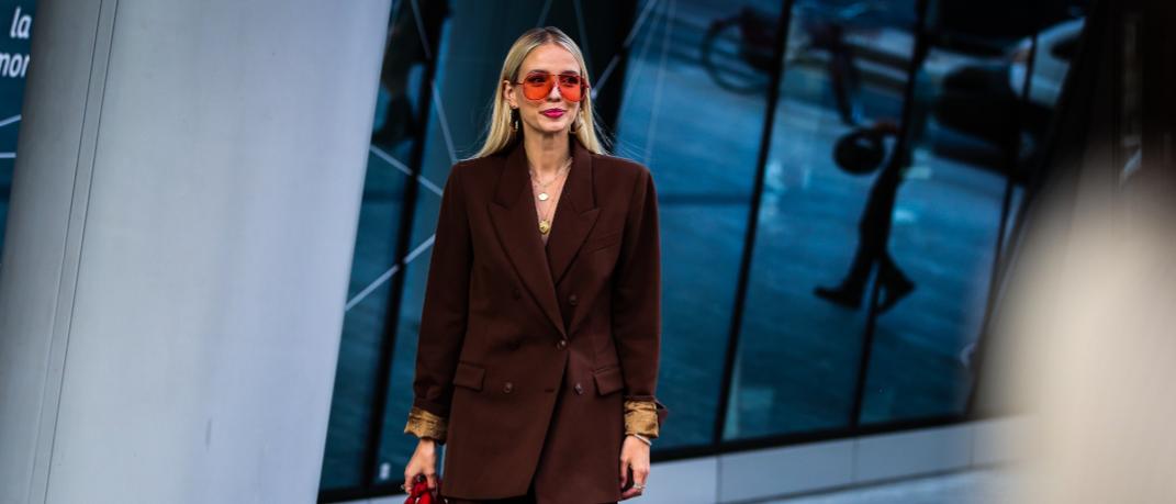 γυναίκα με κοστούμι και γυαλιά ηλίου περπατά στην εβδομάδα μόδας