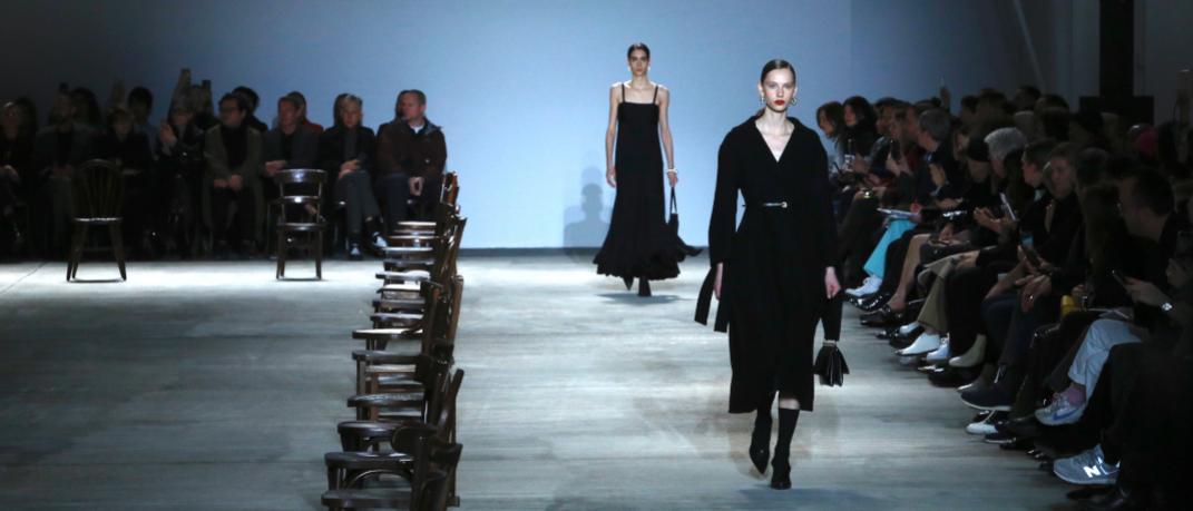 μοντέλο με μαύρο παλτό περπατά στο σόου της Jil Sander