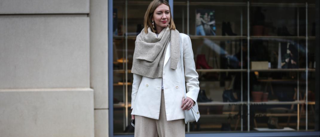 γυναίκα με πλεκτό πουλόβερ και λευκό σακάκι στο δρόμο
