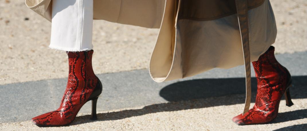 γυναίκα με λευκό παντελόνι και κόκκινες μπότες περπατά στο δρόμο