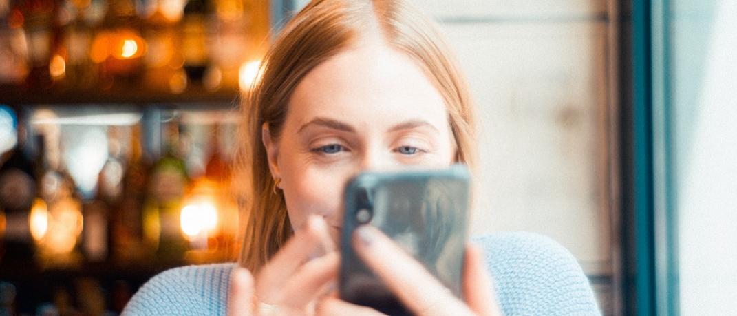 Γυναίκα κρατά κινητό σε καφετέρια