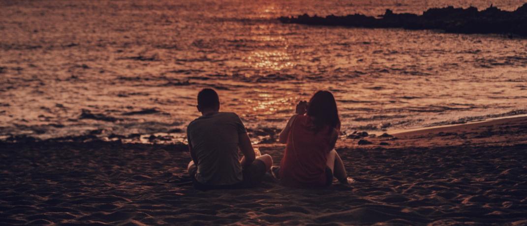 Ζευγάρι σε παραλία βλέπει το ηλιοβασίλεμα