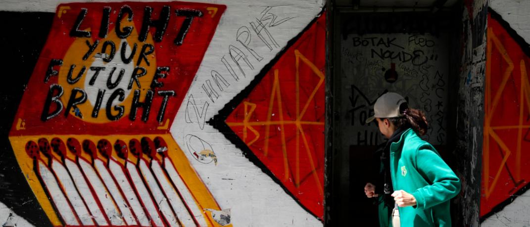 Γυναίκα περπατάει με φόντο τοίχο με γκράφιτι 