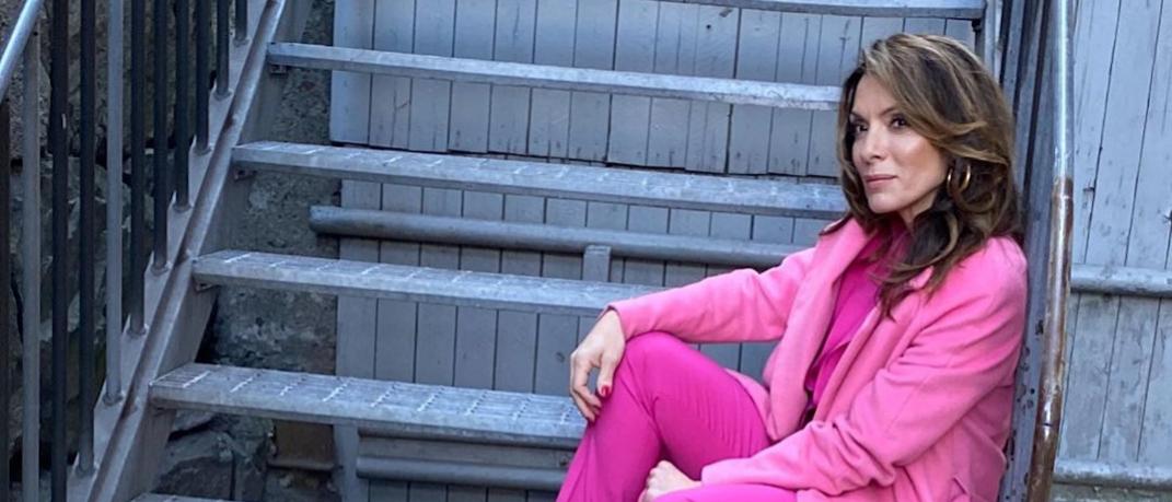 H Αλεξάνδρα Πασχαλίδου με ροζ ρούχα καθισμένη σε σκάλες