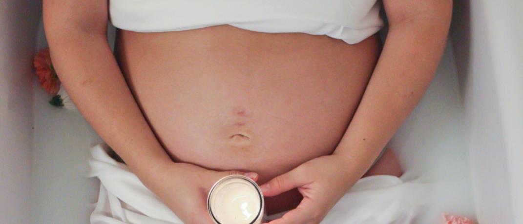 Έγκυος γυναίκα κρατά κρέμα 