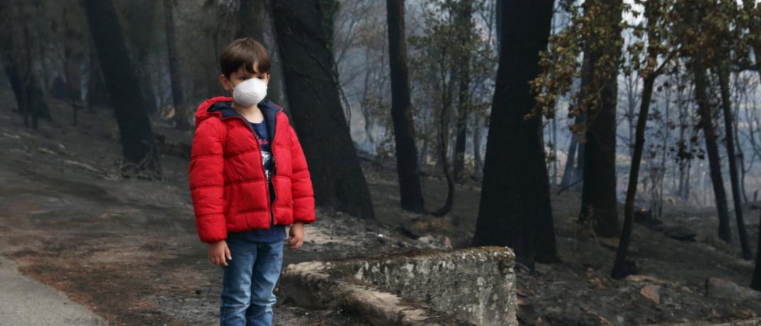 Ένα παιδί με μάσκα σε καμένο δάσος