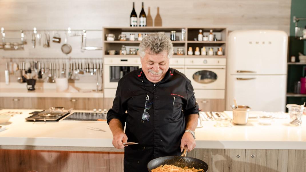 Ο Λευτέρης Λαζάρου στην κουζίνα κρατάει ένα τηγάνι με μακαρόνια 