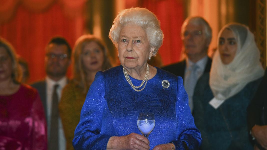 Η βασίλισσα Ελισάβετ με μπλε φόρεμα κρατά ποτήρι