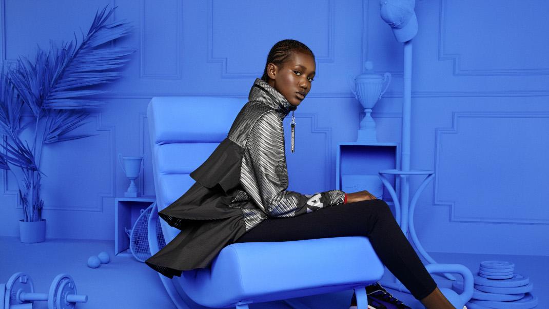 γυναίκα κάθεται σε μπλε δωμάτιο και φορά τη συλλογή Puma X Karl Lagerfeld