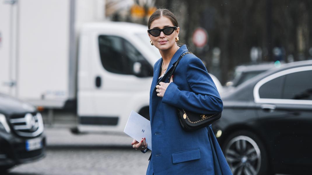 γυναίκα περπατά με γυαλιά και σακάκι στην εβδομάδα μόδας