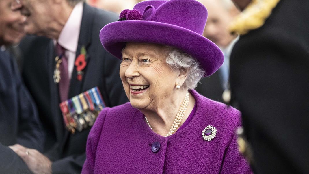 Η βασίλισσα Ελισάβετ με μοβ καπέλο χαμογελά