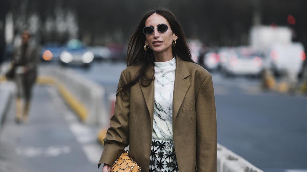 γυναίκα με σακάκι και γυαλιά περπατά στην εβδομάδα μόδας