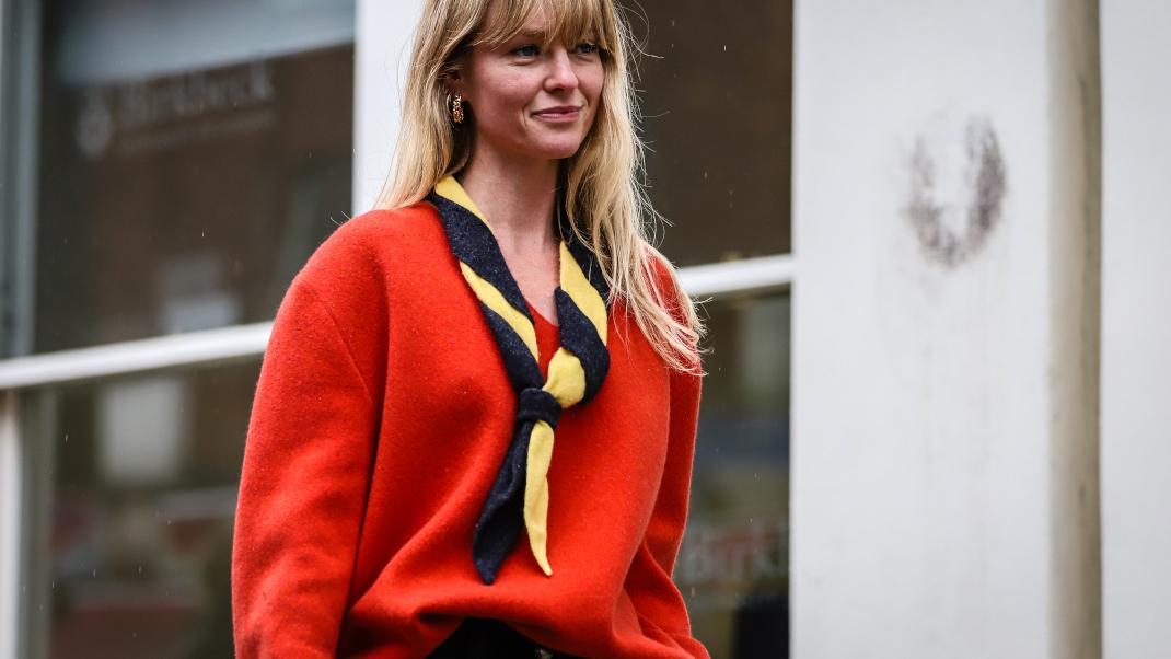 γυναίκα με κόκκινο πουλόβερ και φουλάρι στην εβδομάδα μόδας