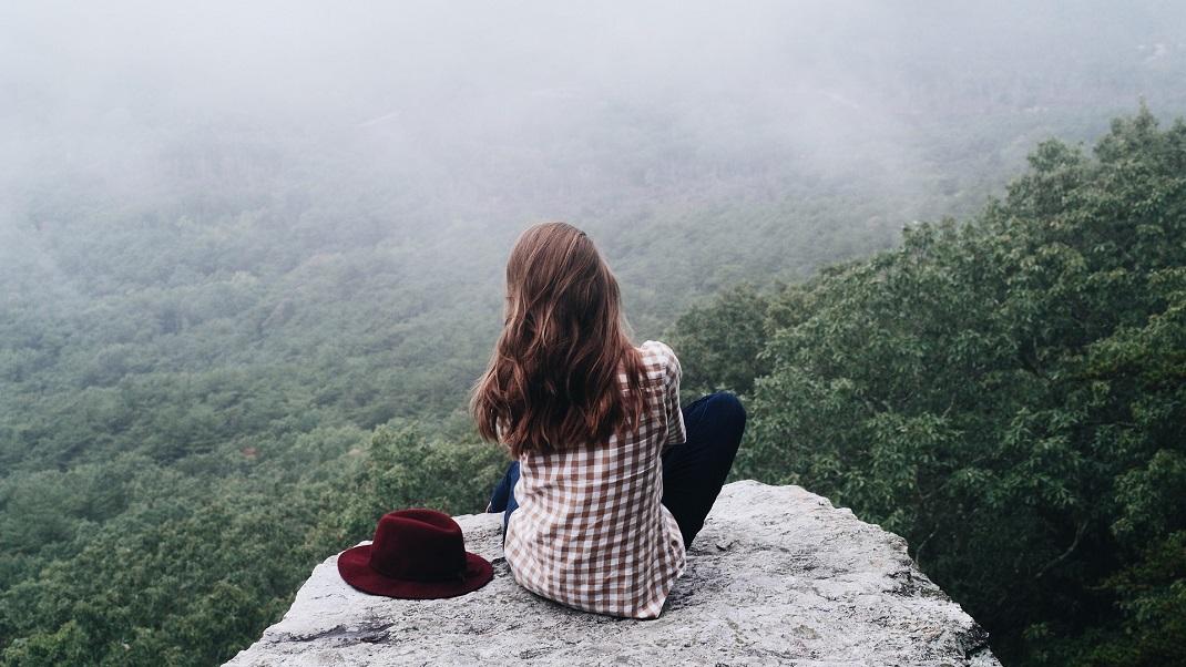 Γυναίκα κάθεται πλάτη και φορά καρό πουκάμισο με θέα δάσος