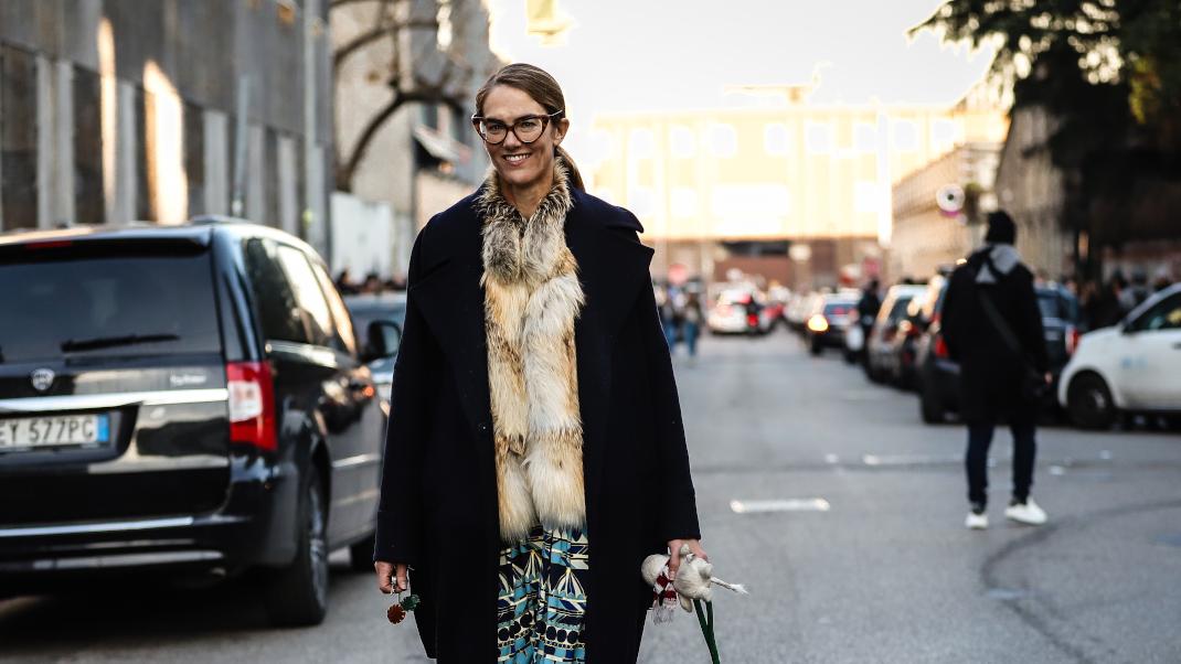 γυναίκα άνω των 40 με παλτό και γούνα περπατά στο δρόμο