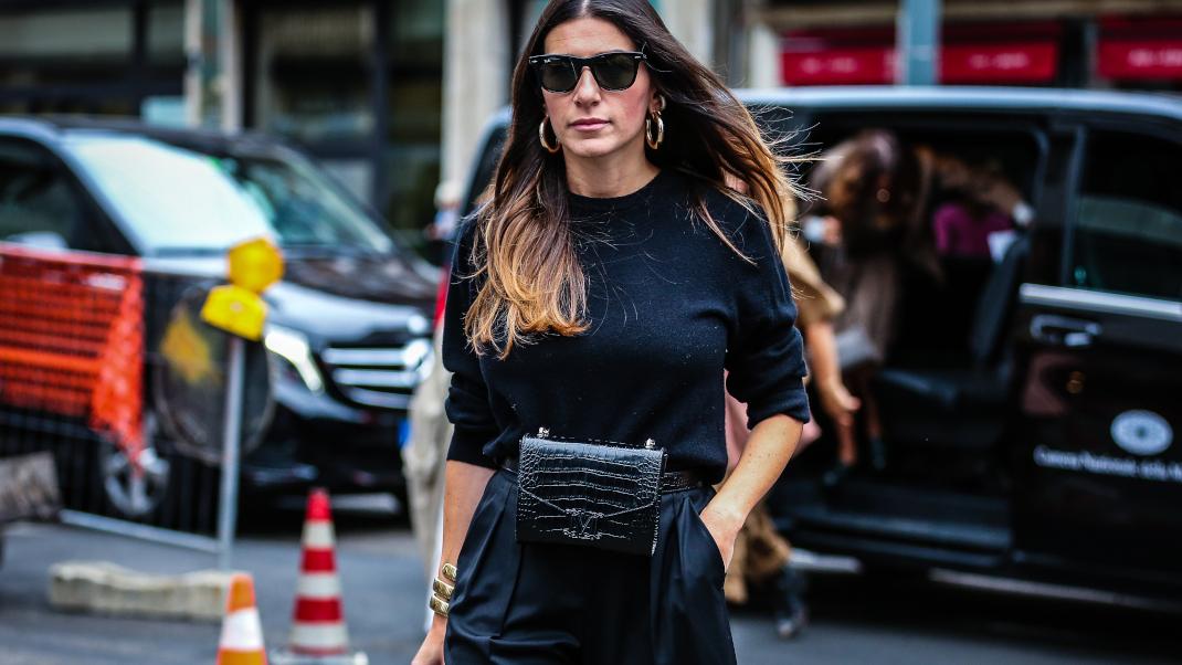 γυναίκα με μαύρη μπλούζα και τσάντα στην εβδομάδα μόδας 