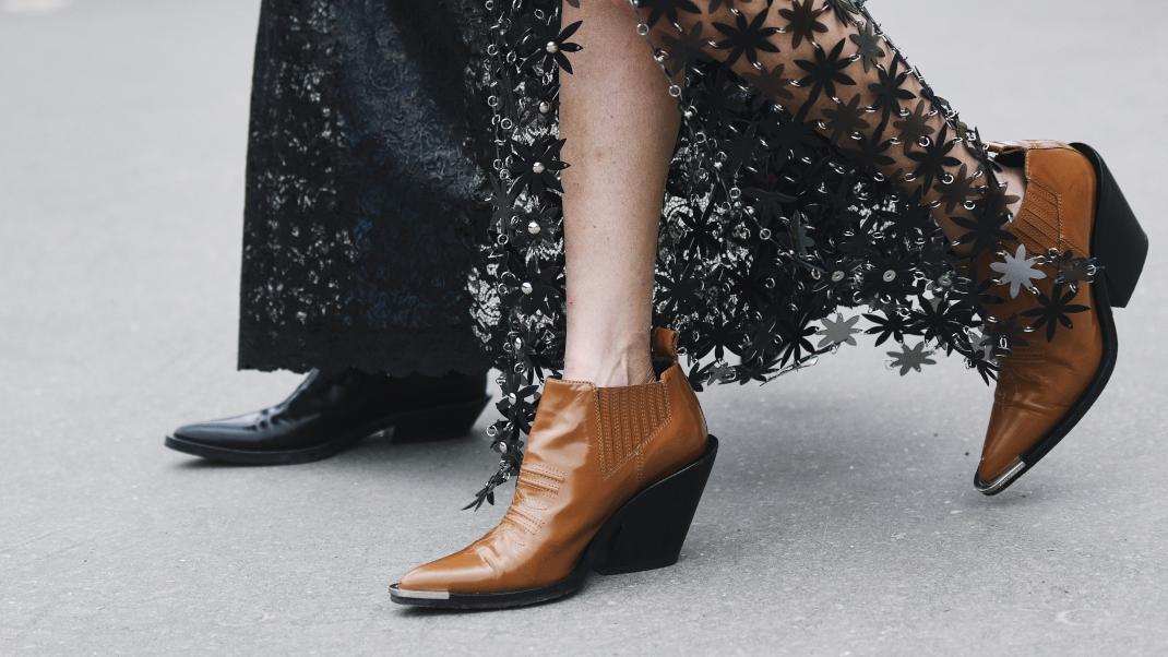 γυναίκα με ankle boots και φούστα περπατά στο δρόμο