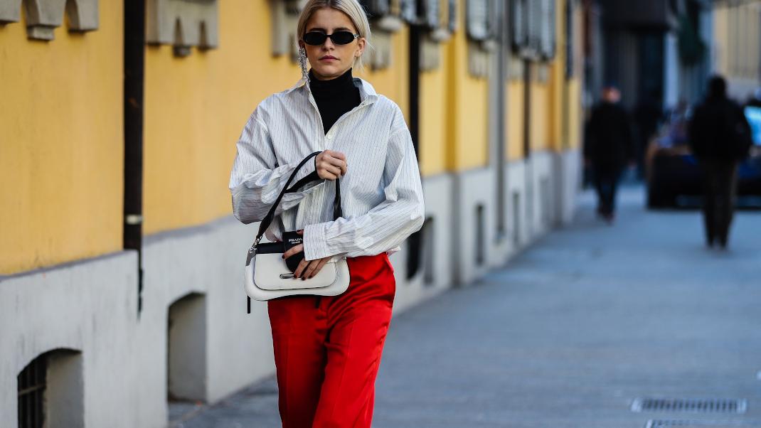 γυναίκα με πουκάμισο και κόκκινο παντελόνι περπατά στο δρόμο