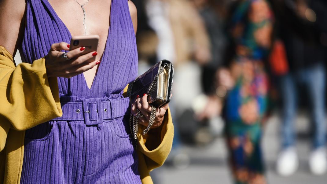 Γυναίκα με ντεκολτέ κρατά τσάντα και κινητό streetstyle