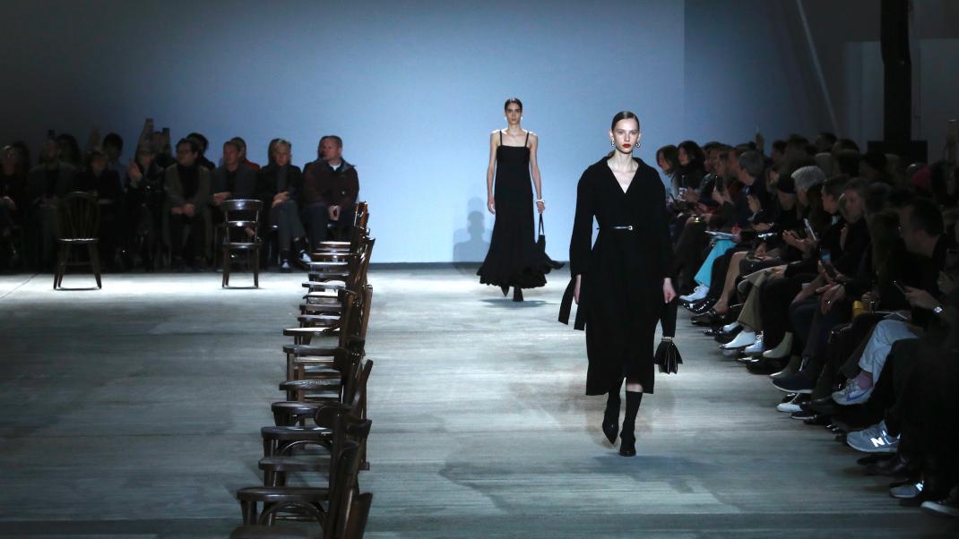 μοντέλο με μαύρο παλτό περπατά στο σόου της Jil Sander