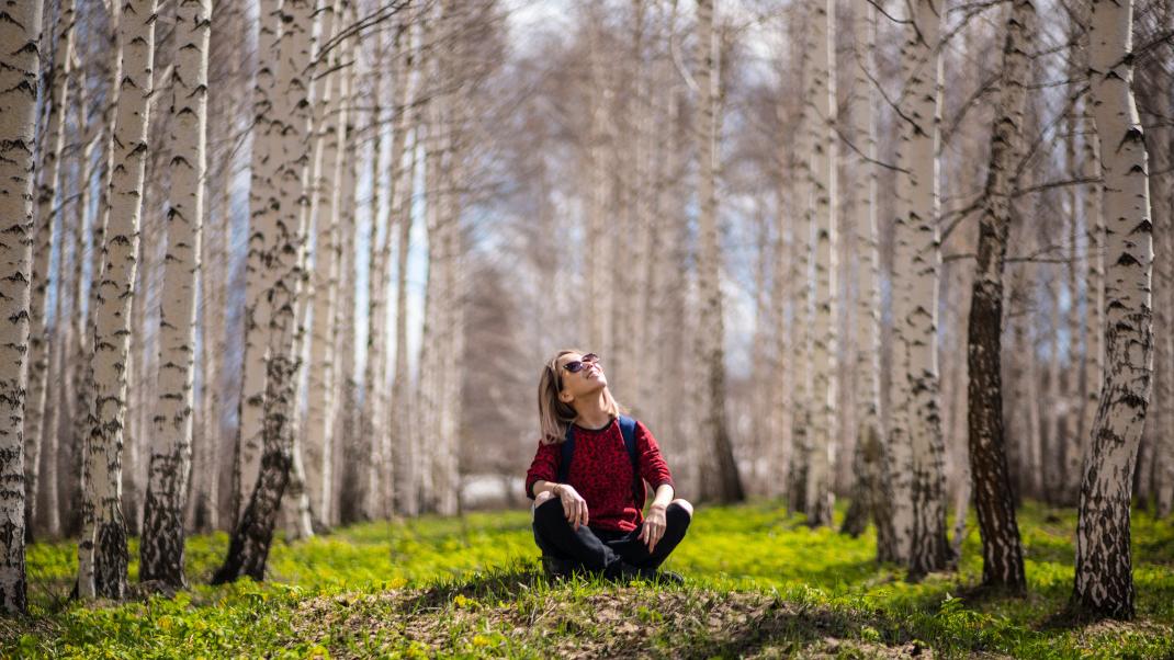 Γυναίκα κοιτάζει τα δέντρα και είναι καθισμένη στο χώμα
