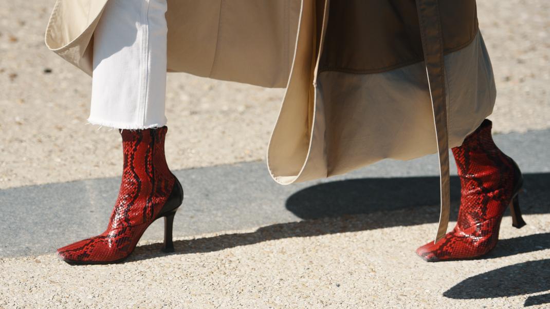 γυναίκα με λευκό παντελόνι και κόκκινες μπότες περπατά στο δρόμο