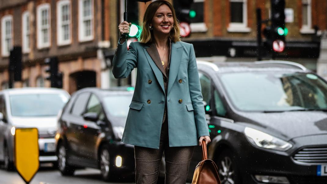 γυναίκα περπατά στην εβδομάδα μόδας με σακάκι και ομπρέλα