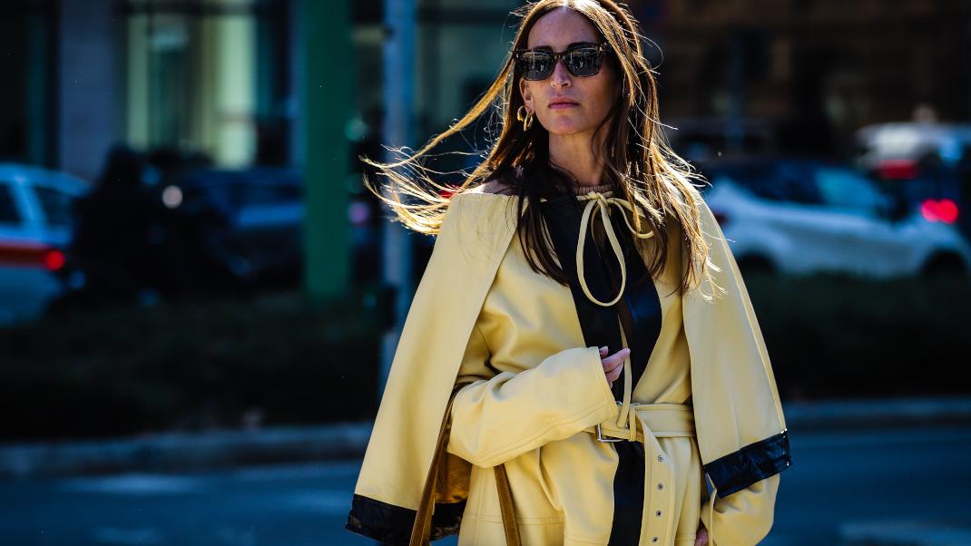 γυναίκα με κίτρινο πανωφόρι και γυαλιά στην εβδομάδα μόδας
