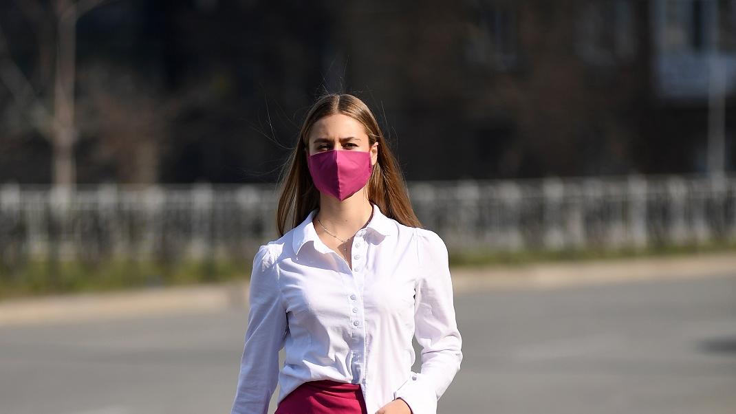γυναίκα με υφασμάτινη μάσκα περπατά