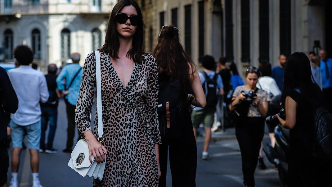 γυναίκα με φόρεμα και γυαλιά περπατά στο δρόμο