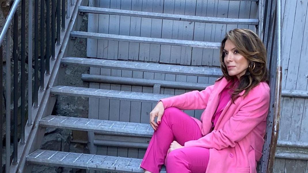 H Αλεξάνδρα Πασχαλίδου με ροζ ρούχα καθισμένη σε σκάλες