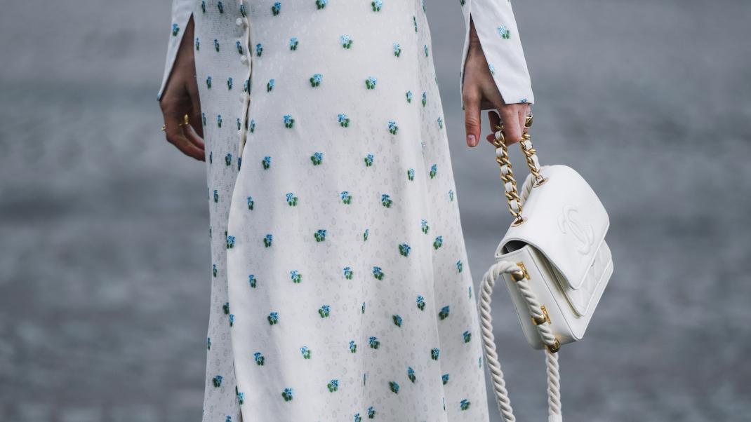 Γυναίκα με floral φόρεμα και λευκή δερμάτινη τσάντα