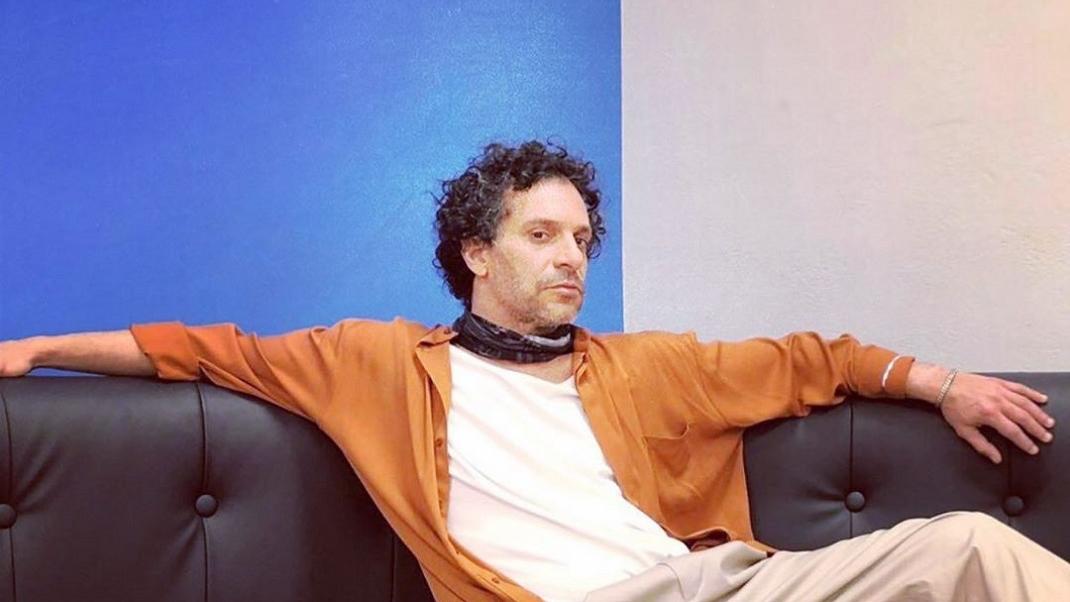 Ο Γιώργος Χρανιώτης με πορτοκαλί πουκάμισο στον καναπέ