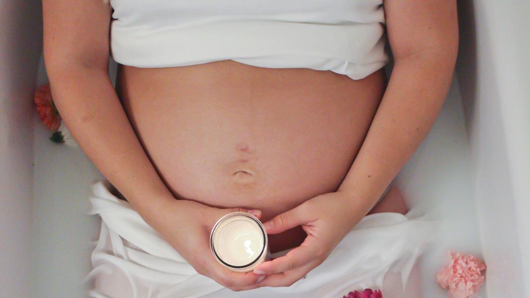 Έγκυος γυναίκα κρατά κρέμα 