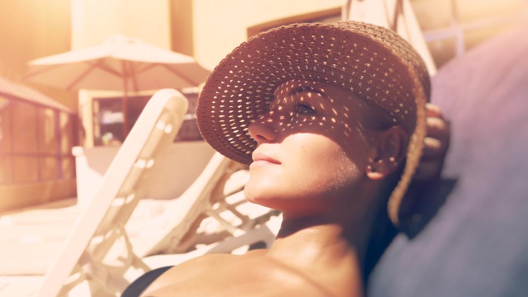 Γυναίκα με καπέλο κάνει ηλιοθεραπεία