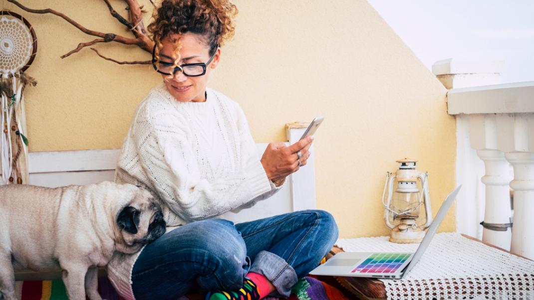 Μια γυναίκα ασχολείται με το κινητό της έχοντας τον σκύλο δίπλα της, Φωτογραφία: Shutterstock