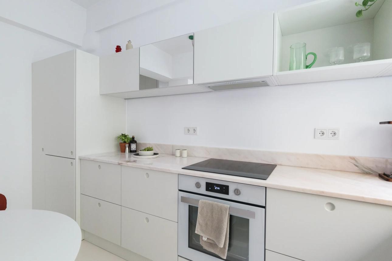 Η κουζίνα «αναπνέει» χάρη στο ύψος του χώρου και την επιλογή να μείνει κενό πάνω από τα ντουλάπια, δημιουργώντας αίσθηση μεγαλύτερου όγκου από τα πραγματικά της τετραγωνικά.