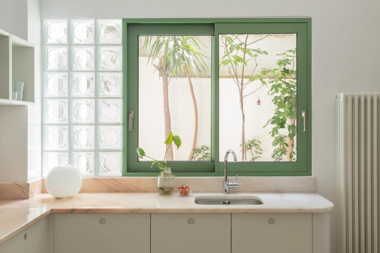 Η κουζίνα λειτουργεί ως μεταβατικός χώρος ανάμεσα στο καθιστικό και την είσοδο, χωρίς να απομονώνεται, διατηρώντας τη συνέχεια και τη ροή του φωτός στο διαμέρισμα.