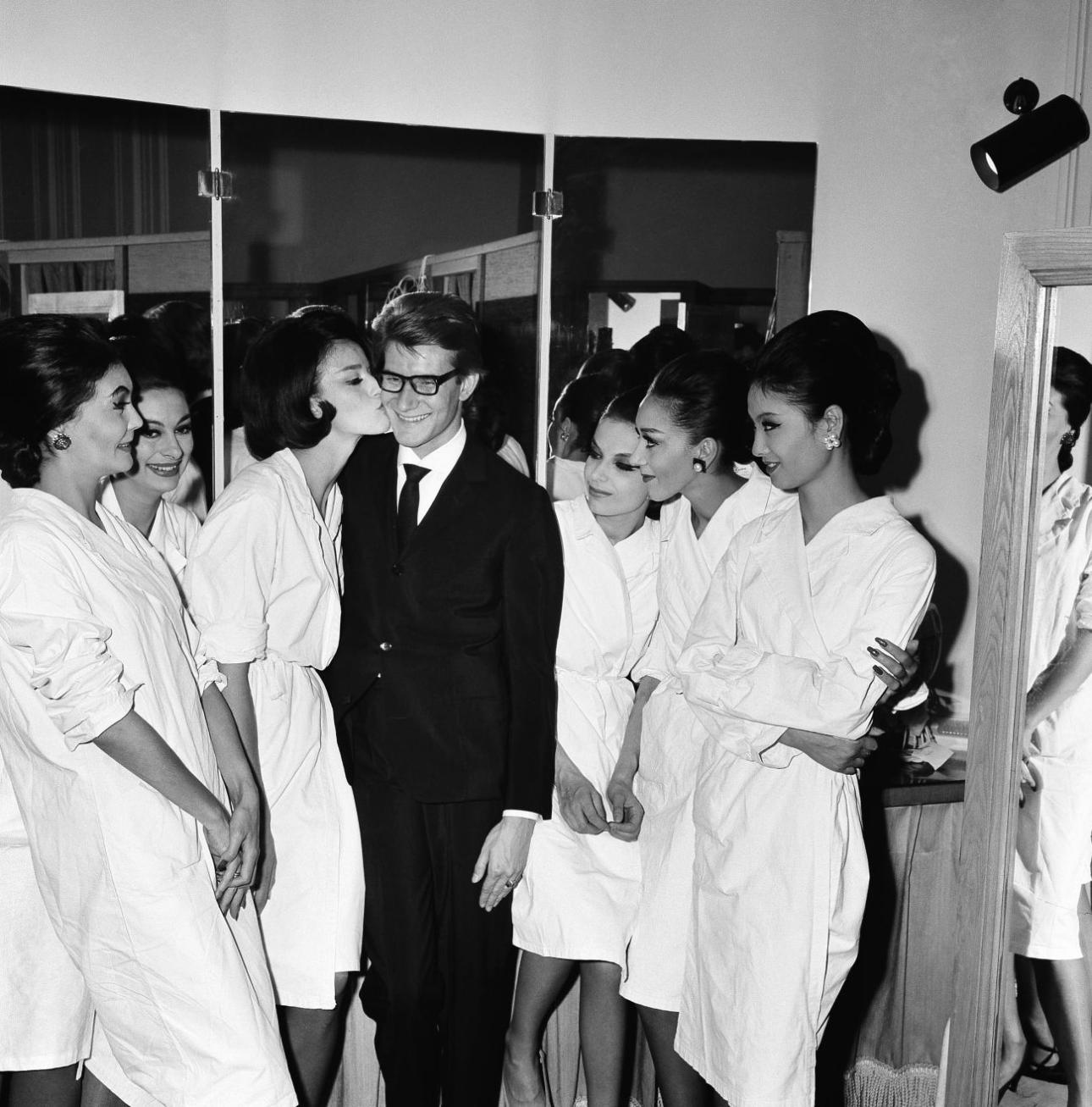 O Yves Saint Laurent δέχεται ένα φιλί από το μοντέλο Eva Helsing μετά την επίδειξη της φθινοπωρινής και χειμερινής του μόδας στο Παρίσι το 1963. Ο Saint Laurent είχε ονομάσει τη συλλογή «Good Mood»./Φωτογραφία: AP Images