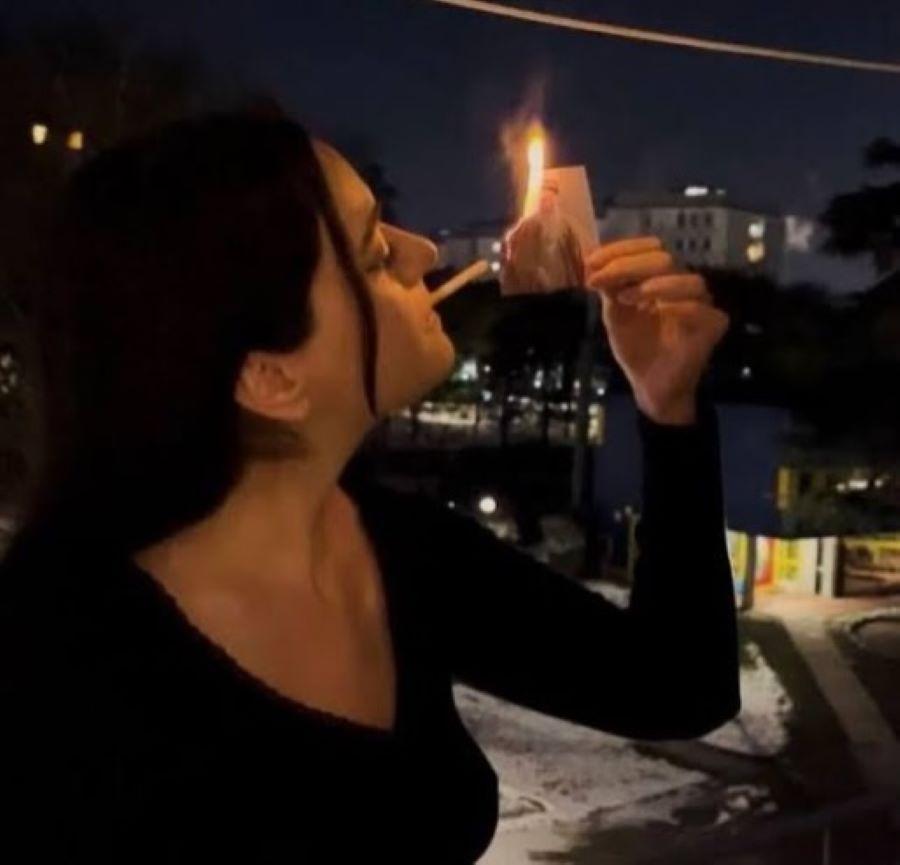 Ιρανή που ανάβει το τσιγάρο της καίγοντας φωτογραφία του Ιρανού ηγέτη Αλί Χανεμεΐ. Φωτογραφία: Instagram/ @irans.feminist.liberation
