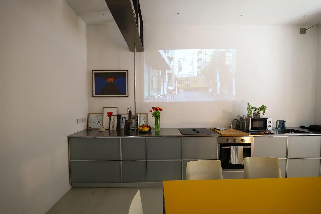 Ο ελεύθερος τοίχος πάνω από την κουζίνα αξιοποιείται για προβολή ταινιών το βράδυ/ Φωτογραφία: Associates Architecture   